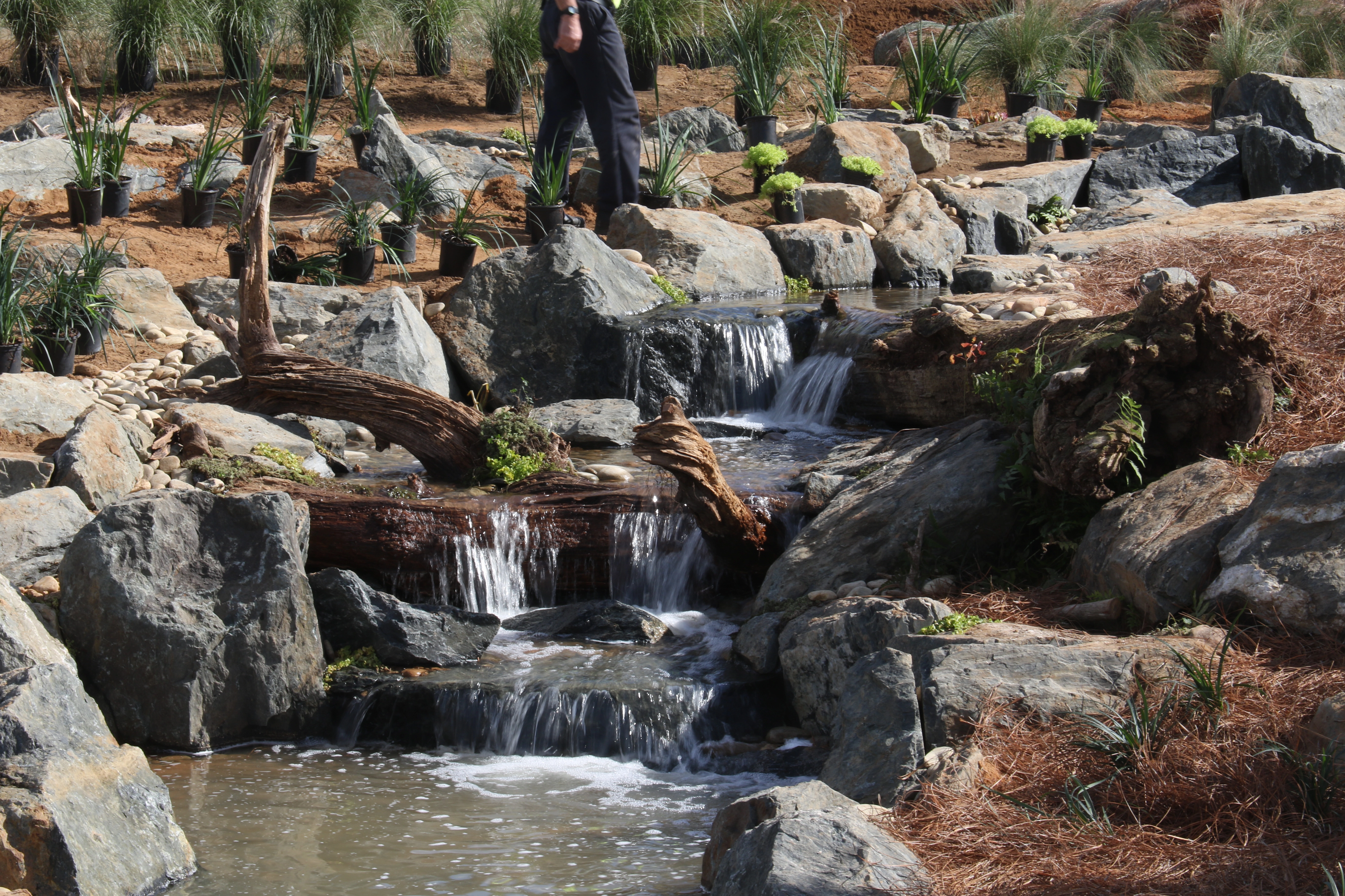 Natural rock waterfall close-up with layered cascades and driftwood
