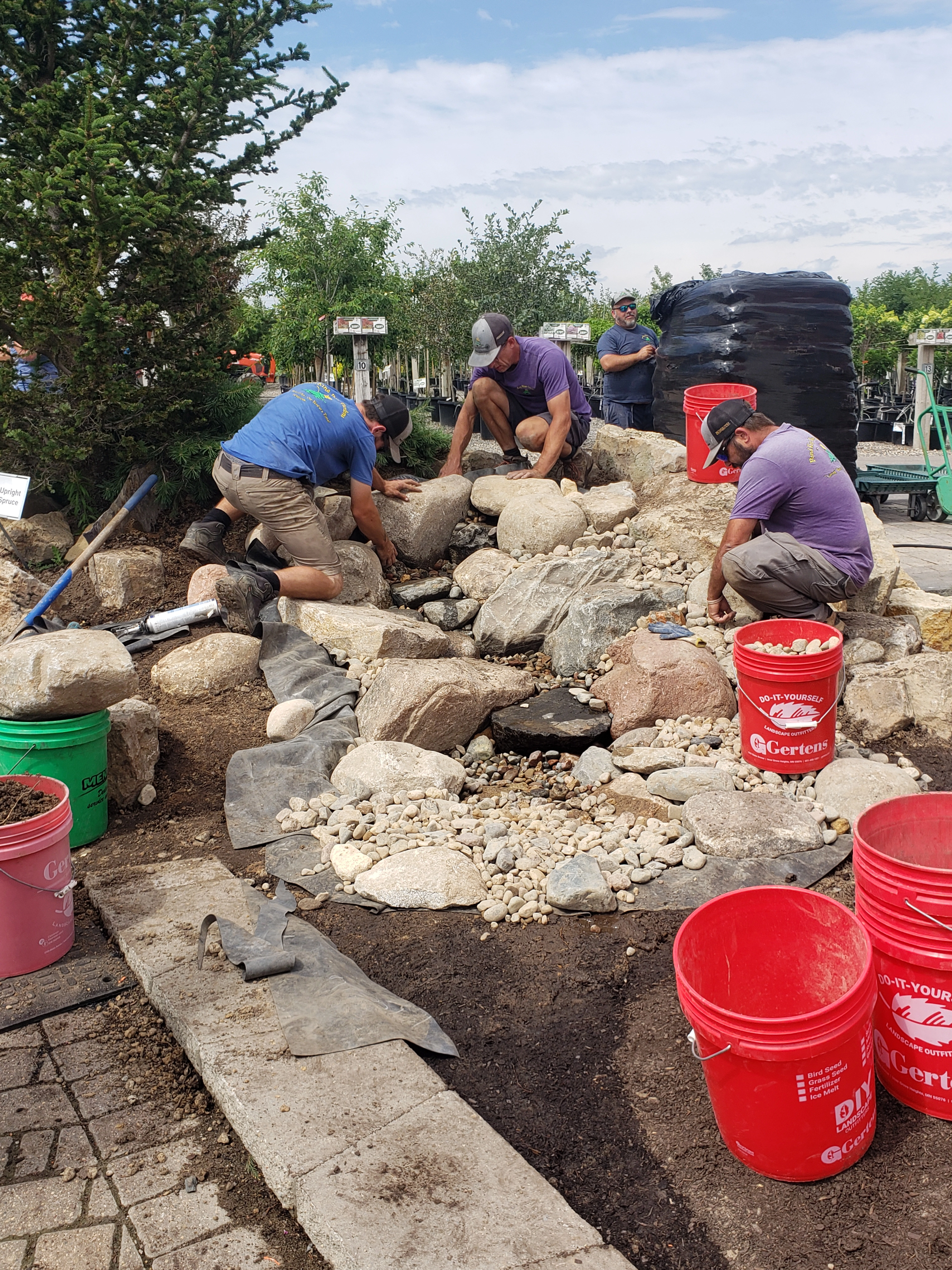 Pondless waterfall nearing completion with natural stone and water path