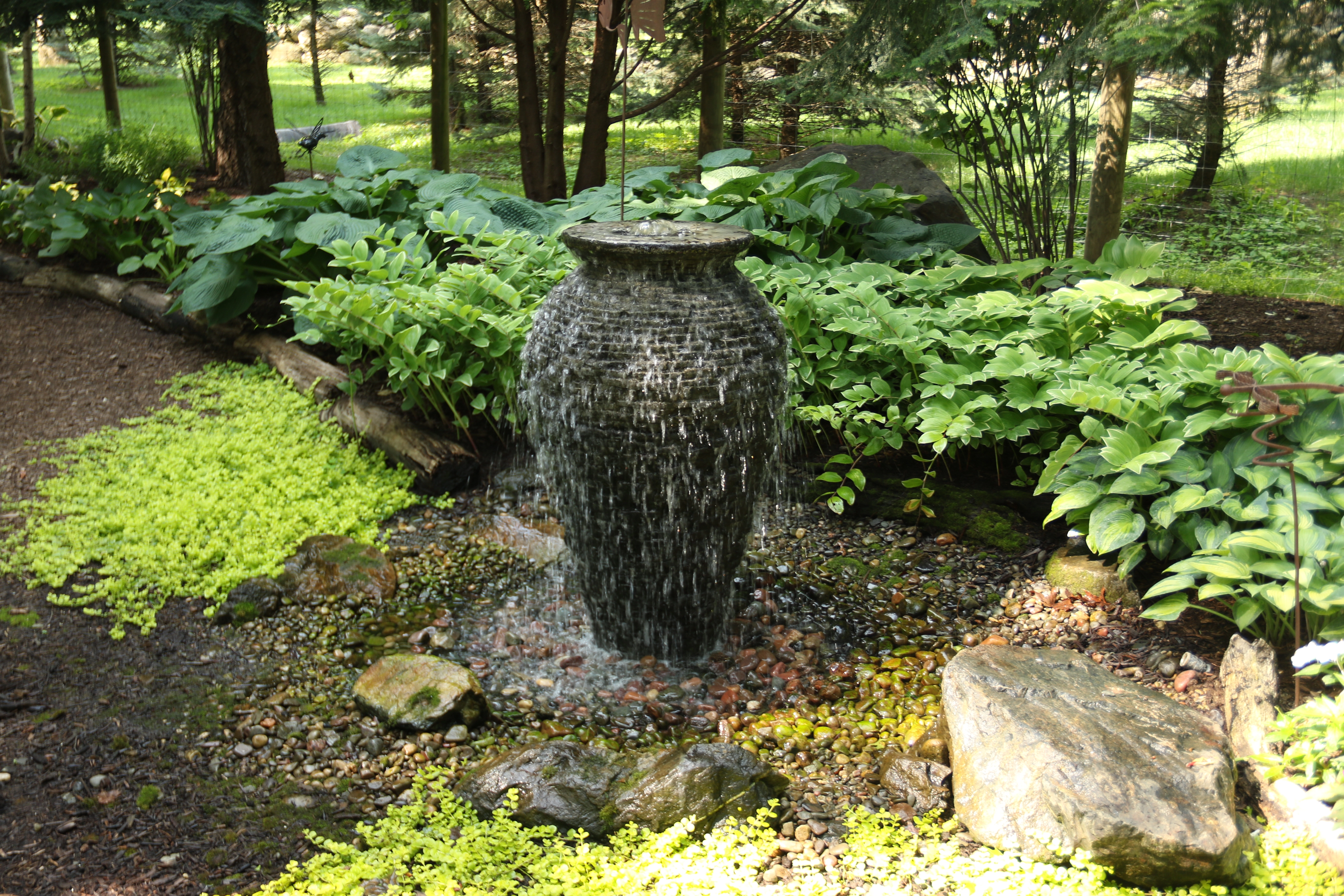 Simple urn fountainscape surrounded by hostas and river rock in Jordan Minnesota