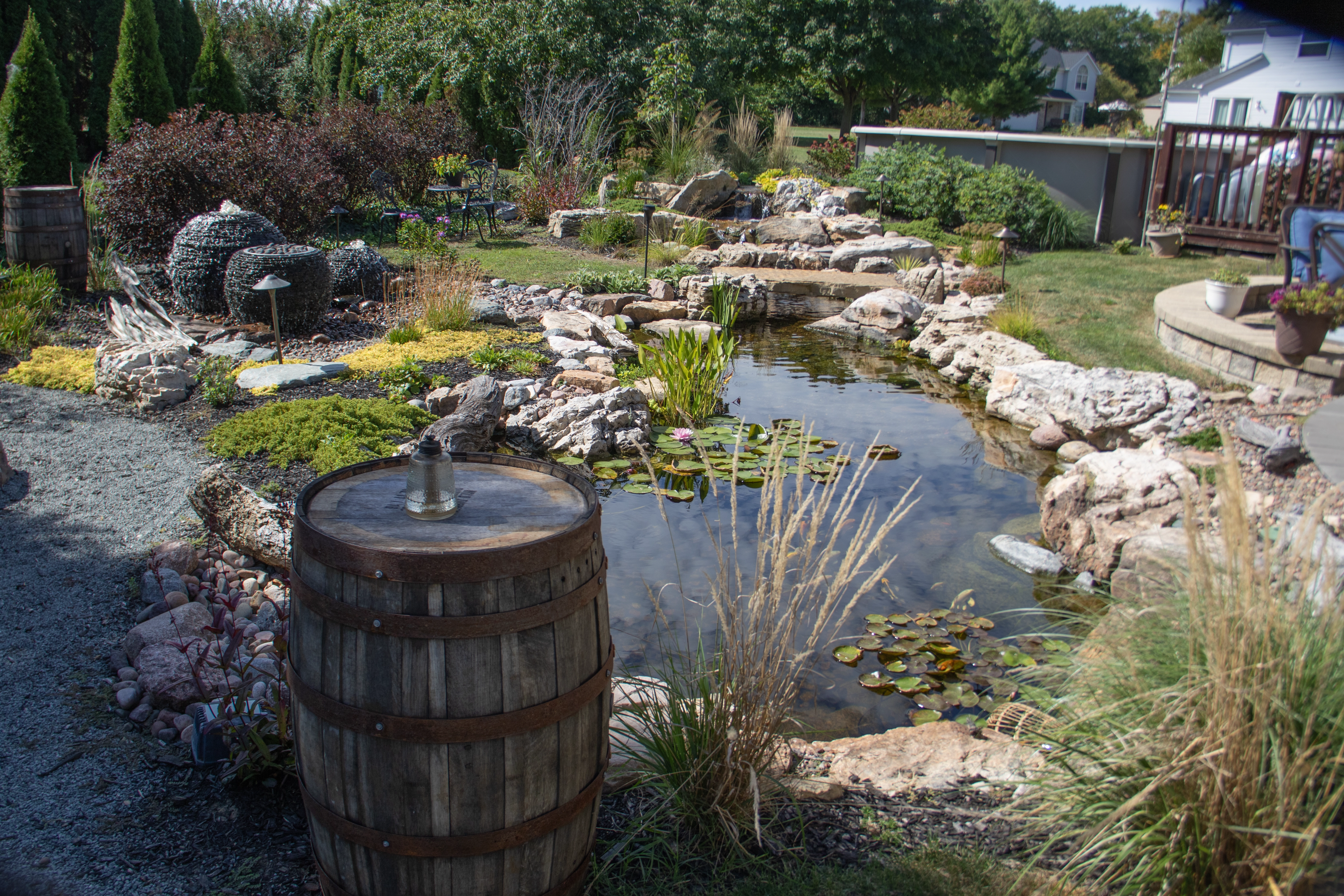 Backyard pond with natural boulders, waterfall, gravel, and landscape planting