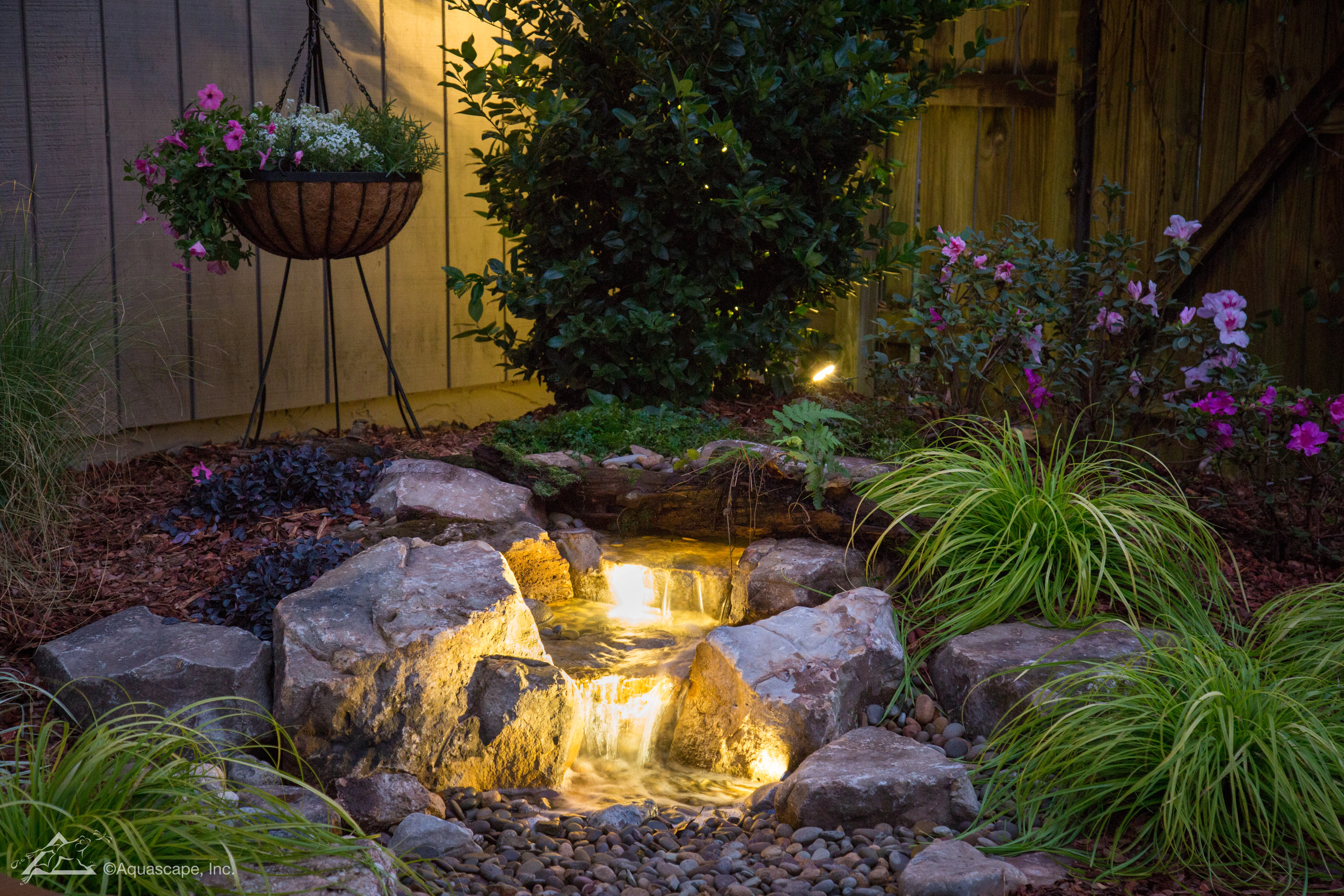 A pondless waterfall lit up with warm white lights