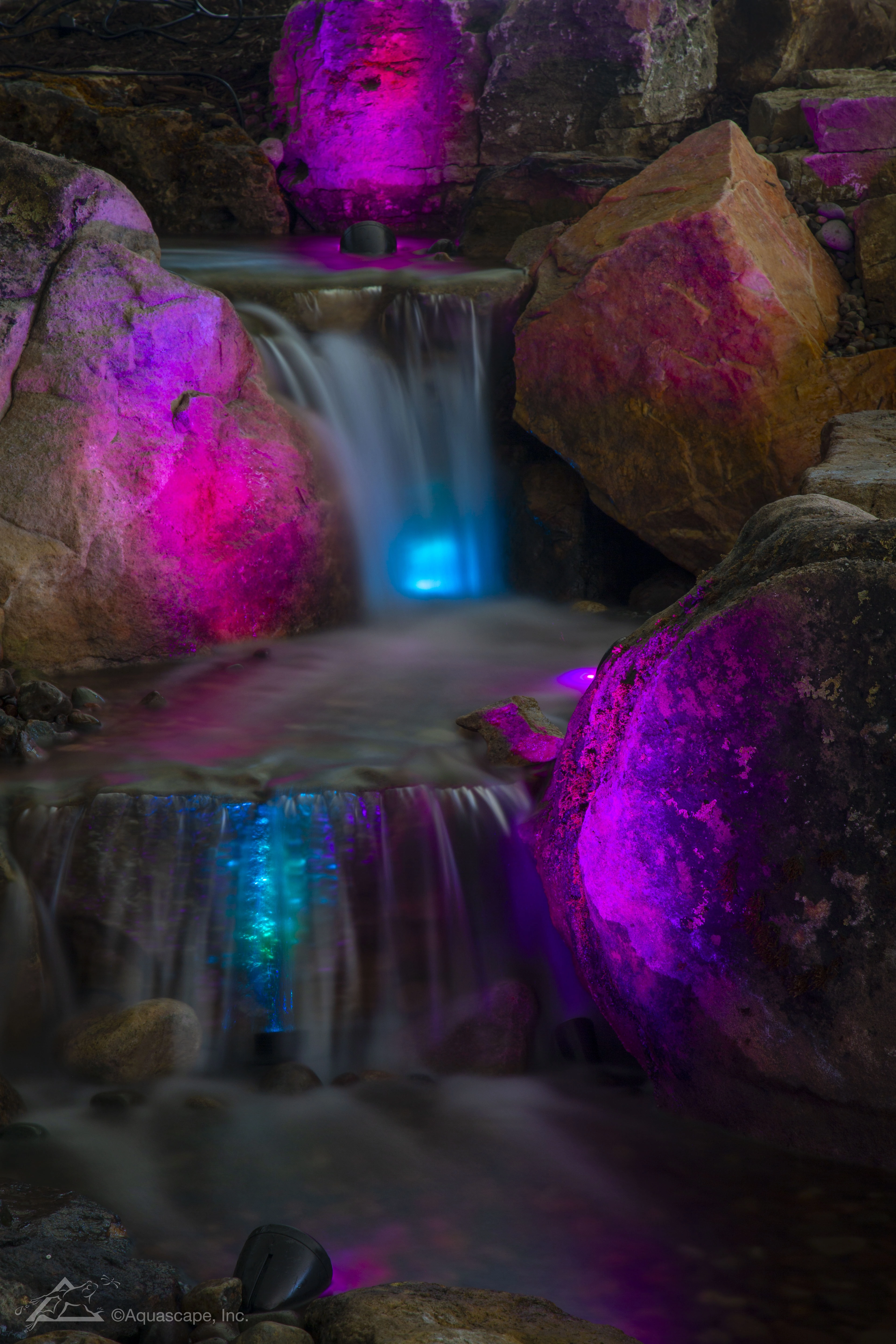 A pondless waterfall lit up with color changing lights