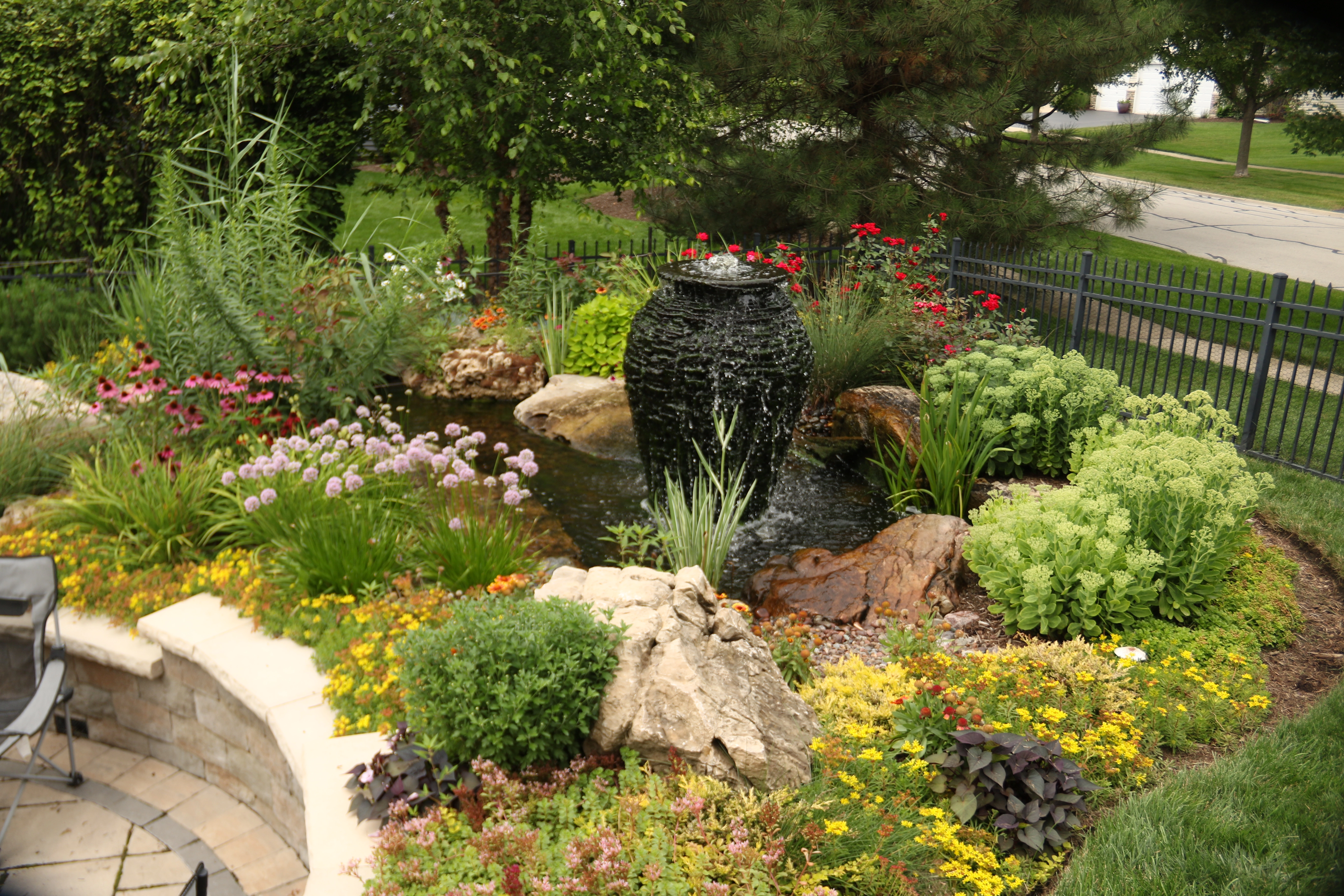 Custom pond with integrated fountain feature and landscaping in residential backyard