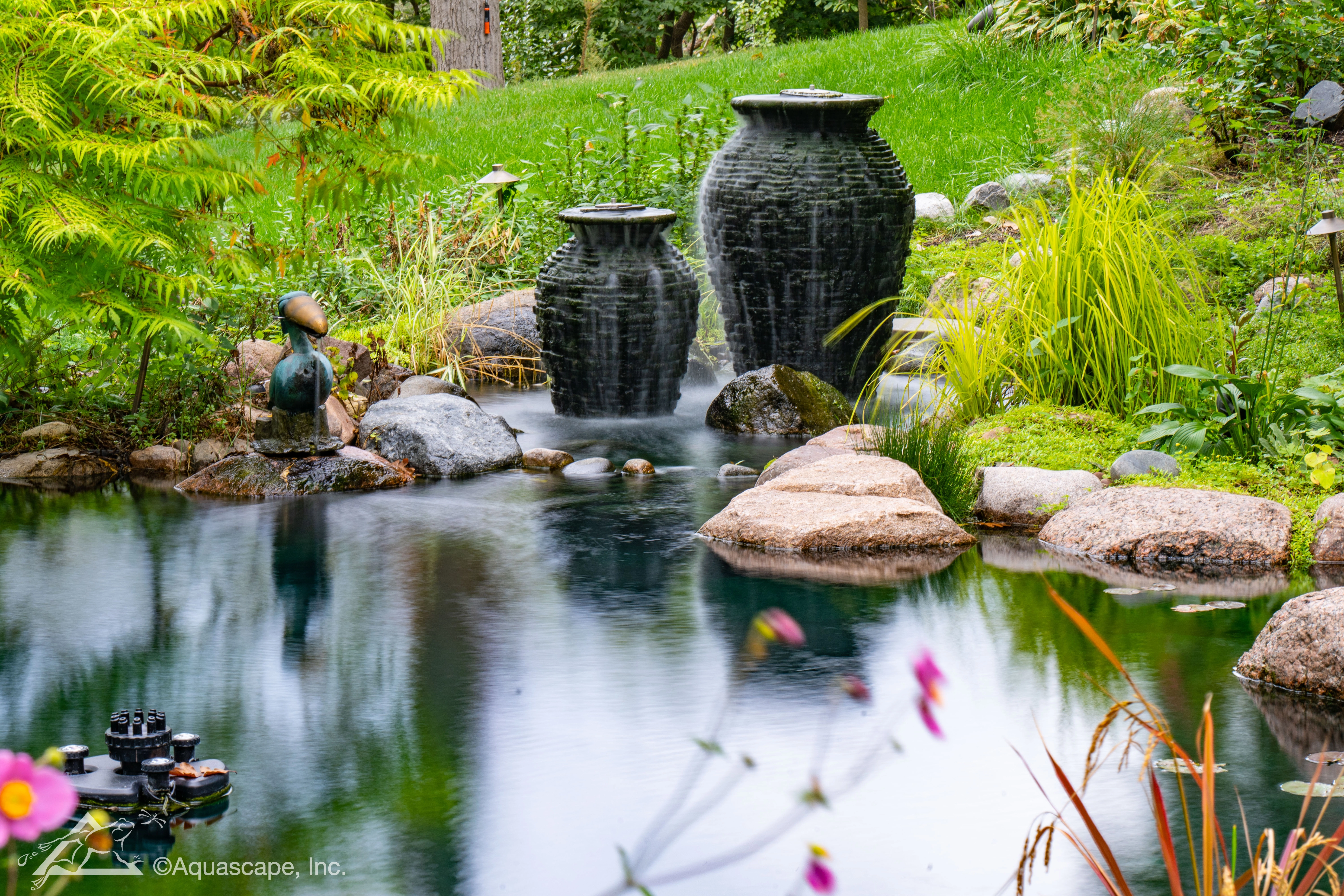 Stacked slate urn fountains near a backyard pond in Victoria Minnesota
