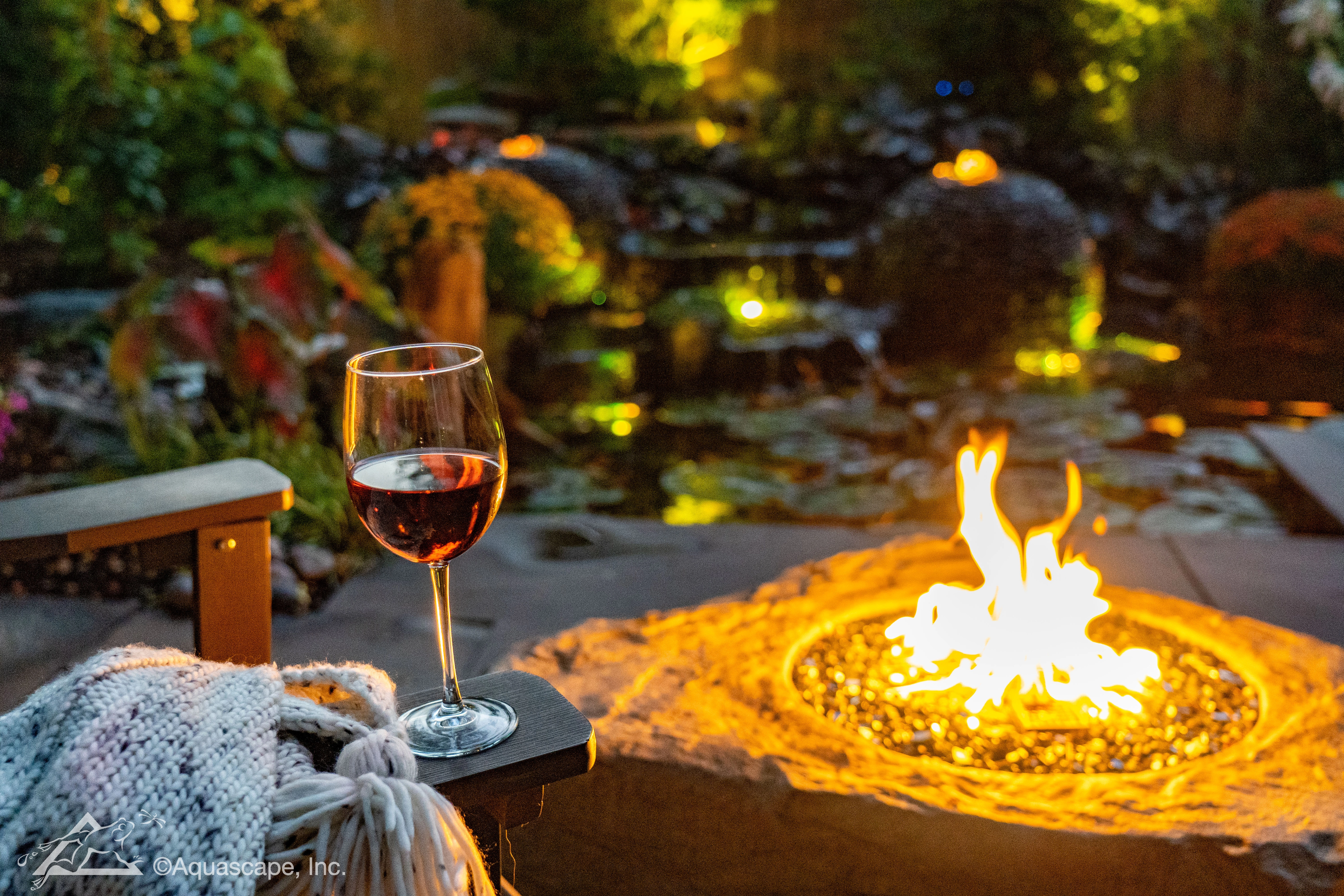 Luxury water feature lifestyle scene with fire, lighting, and outdoor seating